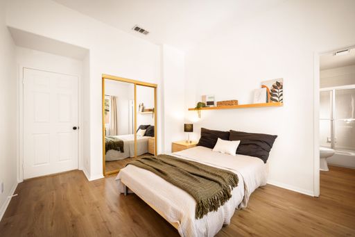 A minimalist bedroom with neutral tones, large windows, modern decor, soft lighting, and cozy furnishings