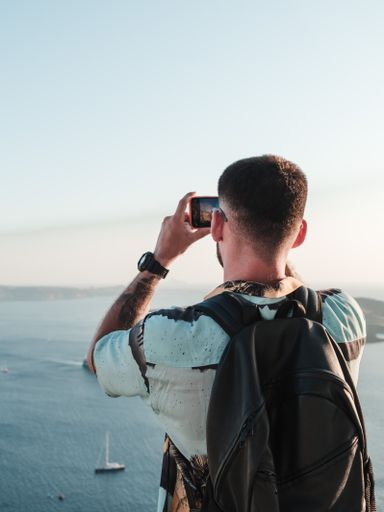A closeup shot from the back of a Caucasian (White) tourist shooting the beautiful place in Santorini, Romania