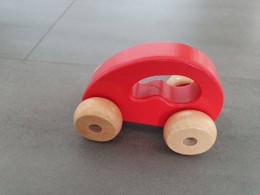 A wooden red toy car on the ground