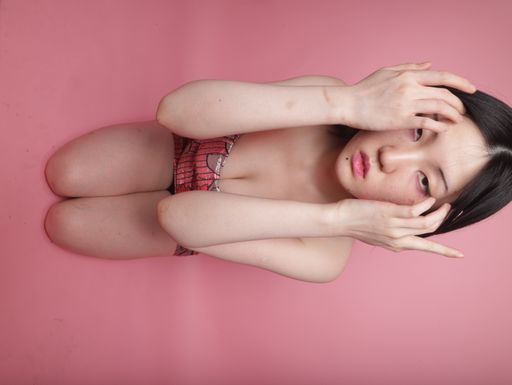 A flipped vertical shot of a seductive South Asian lady wearing a mini dress on a pink background