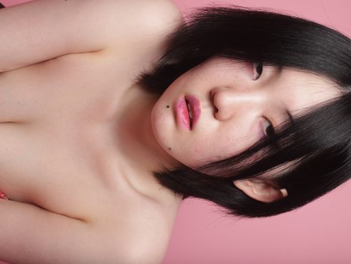 A flipped vertical shot of a young seductive South Asian lady posing isolated on a pink background