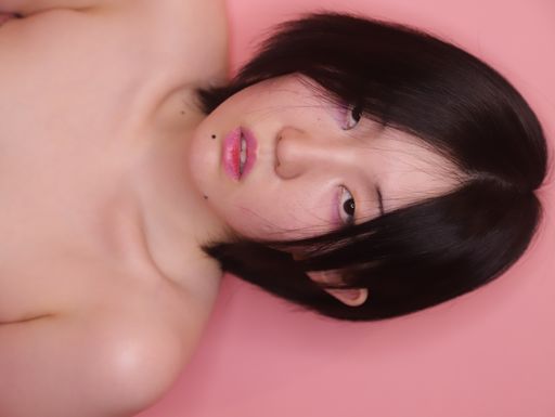 A flipped vertical shot of a young seductive South Asian lady posing isolated on a pink background