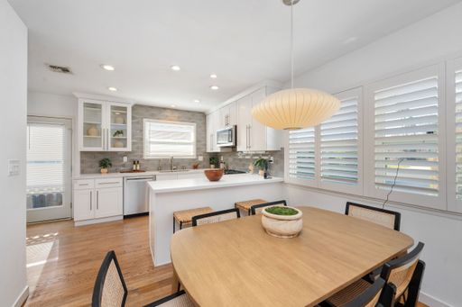 A bright and modern kitchen with white cabinetry, stainless steel appliances, subway tile backsplash, and a large window for natural light.