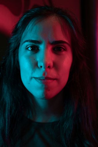A portrait of a young beautiful dark-haired female in blue and pink neon light