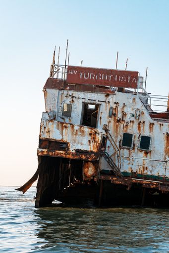 A vertical shot of a Shipwreck in the Sulina Branch of The Danube Delta against a cloudless sky