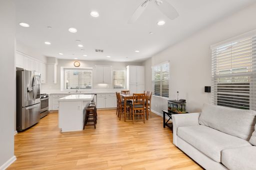 Open-concept kitchen with white cabinets, stainless steel appliances, and a large island for seating and prep