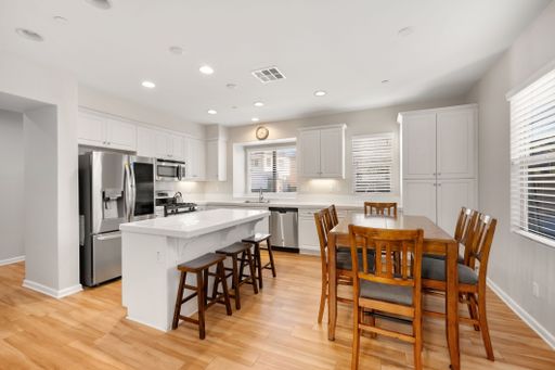 Open-concept kitchen with white cabinets, stainless steel appliances, and a large island for seating and prep