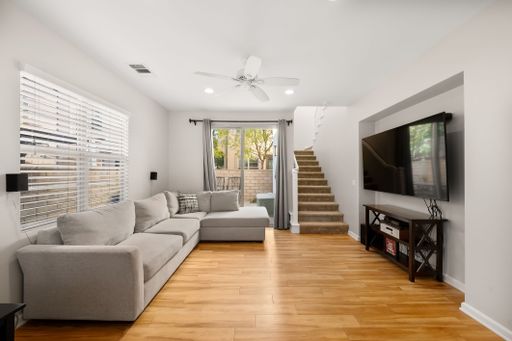 Comfortable living room featuring a large L-shaped sectional, wood flooring, and sliding doors leading to an outdoor patio