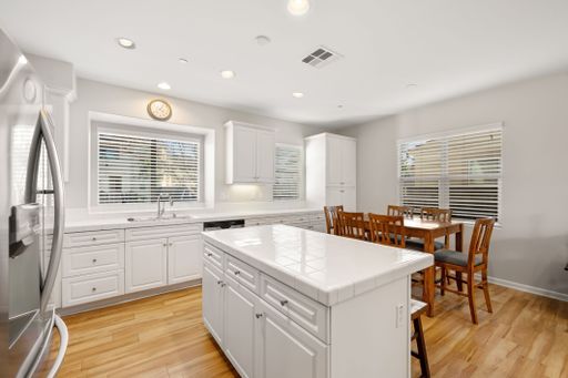 Open-concept kitchen with white cabinets, stainless steel appliances, and a large island for seating and prep