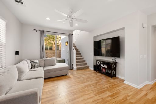 Comfortable living room featuring a large L-shaped sectional, wood flooring, and sliding doors leading to an outdoor patio