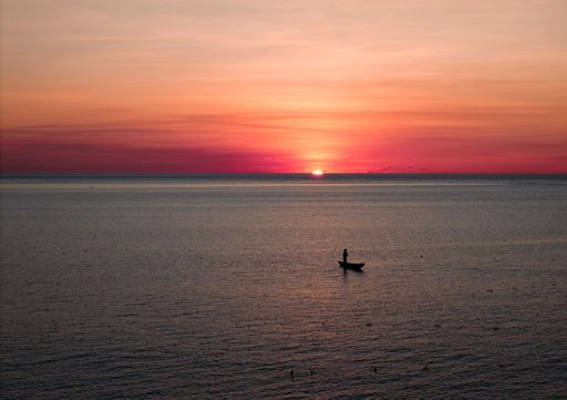 A fisherman in a boat at sunset over Nembrala reef, Rote Island