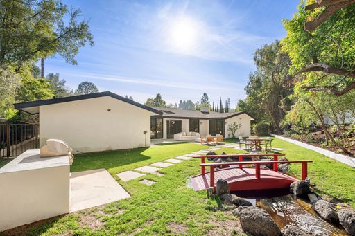 Beautiful outdoor living space featuring a lounge, dining area, and lush greenery for a peaceful and stylish retreat.
