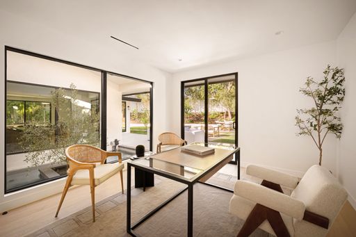 Beautifully designed home office featuring modern furniture, large windows, and an open view of the landscaped backyard.