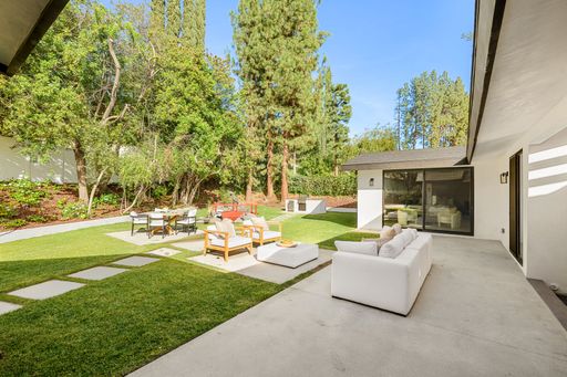 Beautiful outdoor living space featuring a lounge, dining area, and lush greenery for a peaceful and stylish retreat.