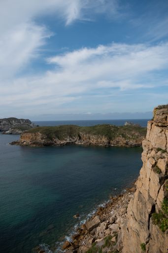 A vertical shot of a beautiful seascape with cliffs against cloudy sky