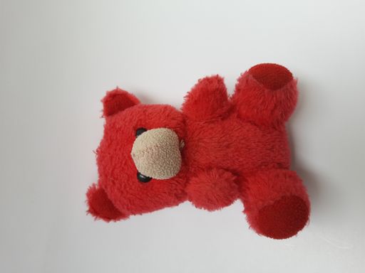 A top view of a small, red soft toy bear isolated on a white background