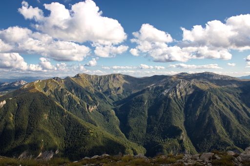 A high angle shot of mountainous landscape with peaks under sunlight