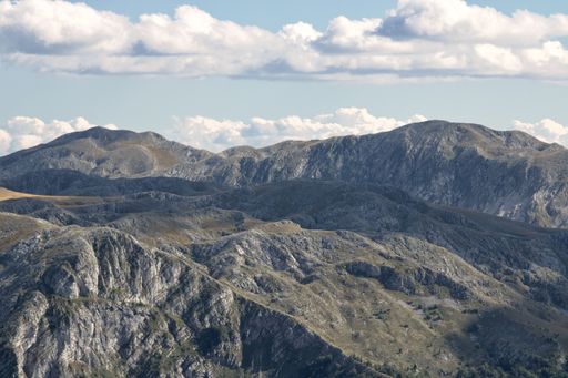 A high angle shot of mountainous landscape with layers of peaks seen under cloudy sky