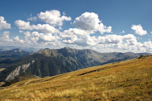 A high angle shot of mountainous landscape with peaks and a plato in the foreground under sunlight