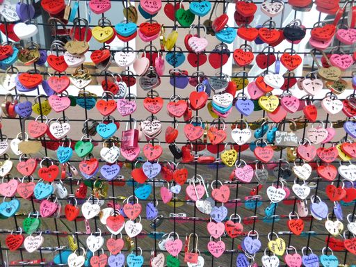 Colorful love locks attached to a metal fence, symbolizing love and commitment, captured in vibrant detail.