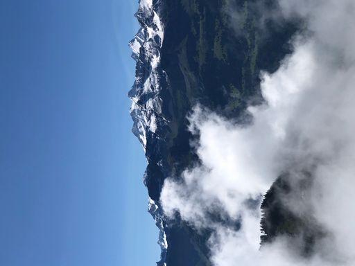 A vertical shot of rocky hills covered in the fog under the sunlight and a blue sky