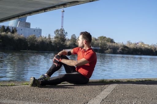 A closeup shot of a young male in sports costume sitting on the body of the river