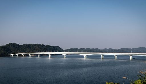 White bridge over calm river with green hills and blue sky in Hangzhou, China