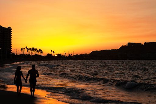 The silhouette of a couple walking on a sandy beach at scenic sunset