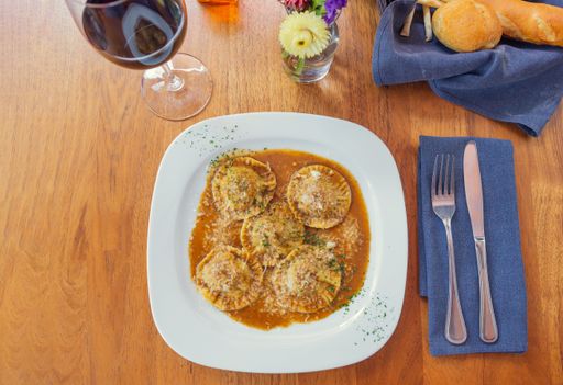 A top view of ravioli topped with herbs and cheese on a plate