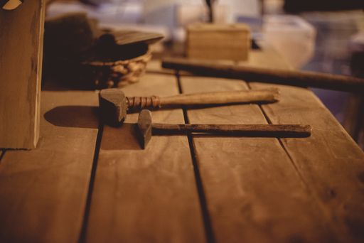 A closeup of hammers on a wooden table under the lights with a blurry background
