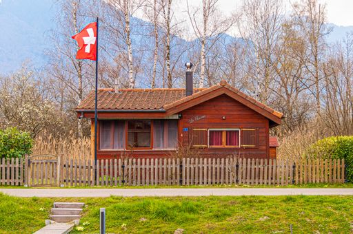 A beautiful shot of a cozy log cabin surrounded with trees in Les Grangettes Nature Reserve, Switzerland