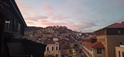 Charming view of a hillside town at dusk, with traditional architecture and colorful sky, capturing the essence of a serene evening.