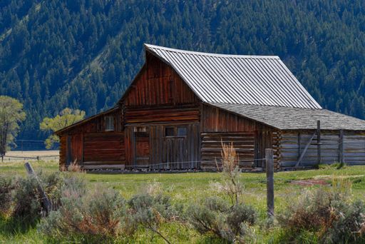 A closeup shot of a beautiful and small farm house in a great natural area in front of a mountain