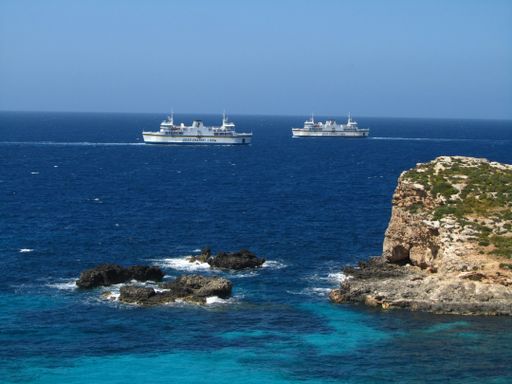 Gozo Channel ferry ships, used for transport between the islands of Malta and Gozo, as seen from the island of Comino. Crossing the deep sea and waves