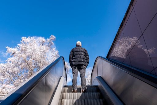 A man coming out of the subway with the escalator