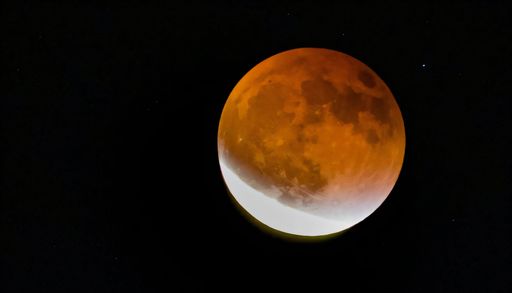 A stunning lunar eclipse with a reddish moon against a dark night sky.