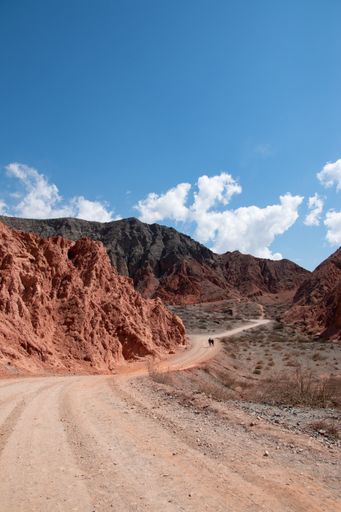 A vertical shot of a route between rural canyons on a sunny, cloudy day