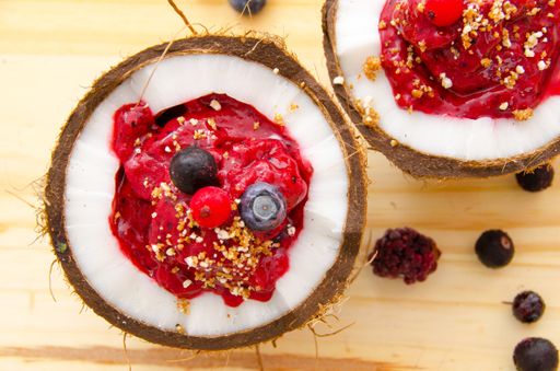 A top view of a delicious fruit salad with jelly and different types of berries served on a coconut