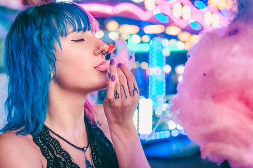 A closeup shot of an attractive young female enjoying eating cotton candy in an amusement park