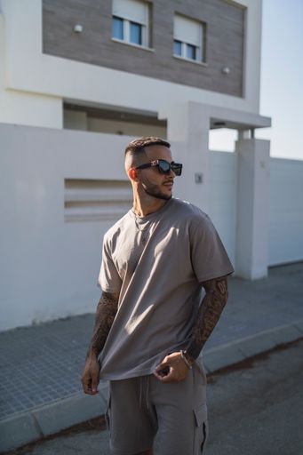 A vertical shot of a young stylish caucasian male with tattooed arms outdoors