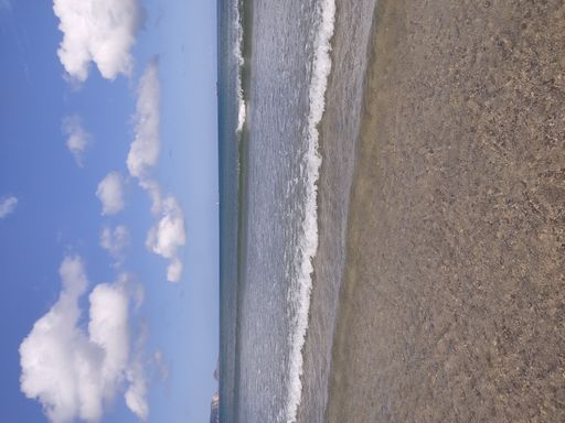 A beautiful view of ocean waves washing over beach sand on a warm sunny day