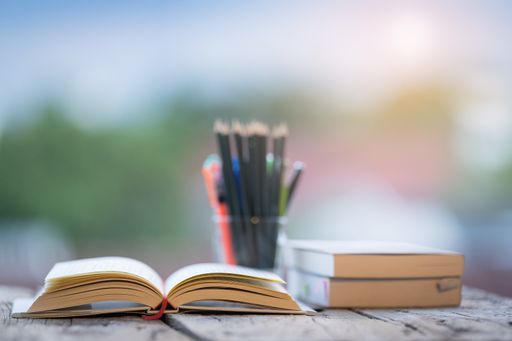 Several books, pencils on a wooden table on a blurred background