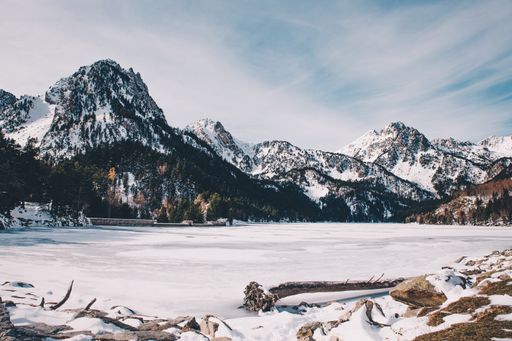 A beautiful view of snow-covered mountains and a frozen Sant Maurici lake under a cloudy sky in Spain