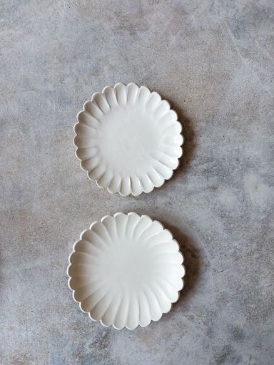 A selection of handmade stoneware ceramics in various glazes and decorations on warm stone background