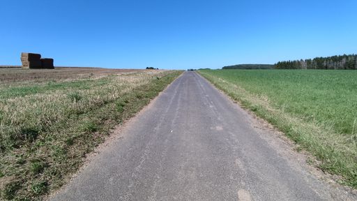 A high angle shot of an asphalt road through agricultural lands on a clear day