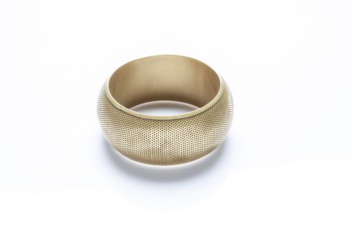 A closeup shot of a golden bracelet in a studio on white background