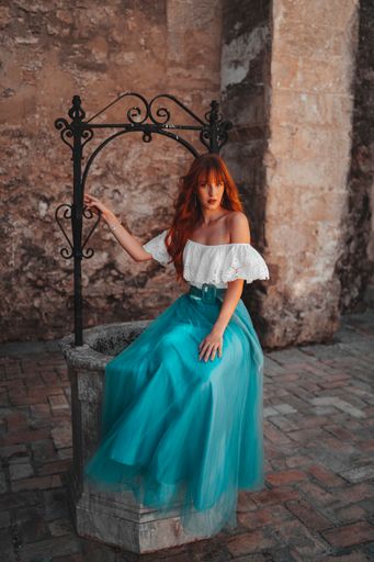 A vertical shot of an attractive Caucasian female wearing a beautiful dress posing in an old buildin