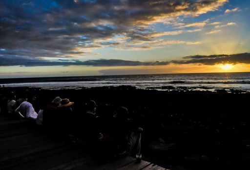 A wide angle shot of a sunset at the beach under a sky full of clouds