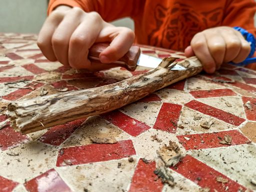 A child carving a stick with a knife