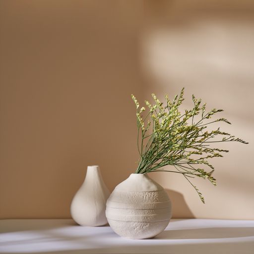 Dry sea-lavender in a white ceramic vase against a beige wall